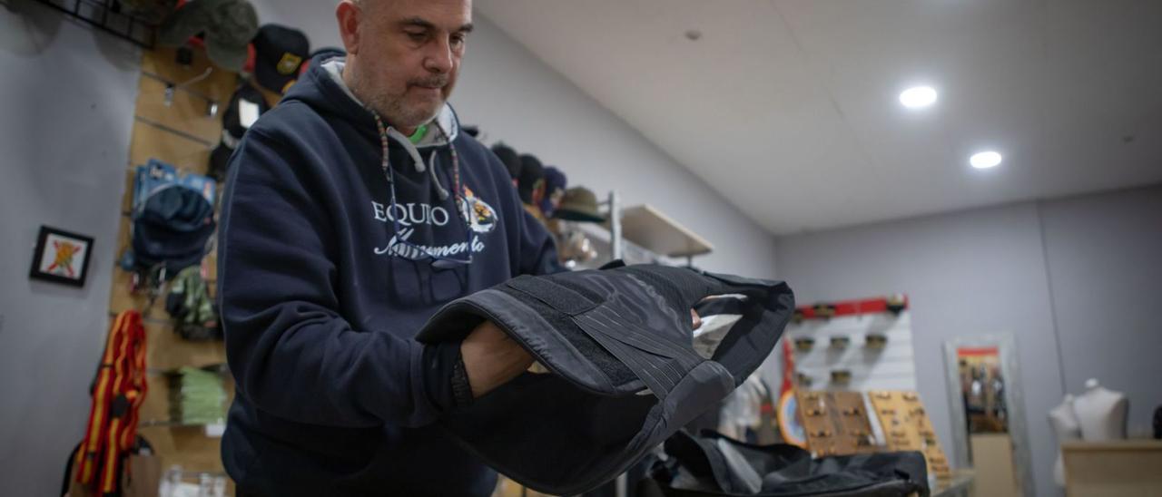 El dueño de la tienda de ropa militar M&amp;M de Paterna, José, muestra un chaleco antibalas. | LOYOLA PÉREZ DE VILLEGAS