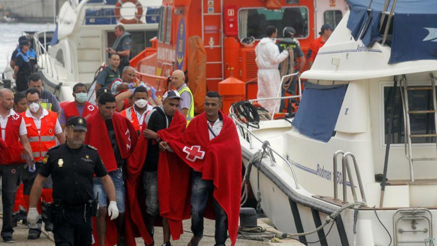 Varios inmigrantes acompañados por policías a su llegada al muelle de San Pedro.