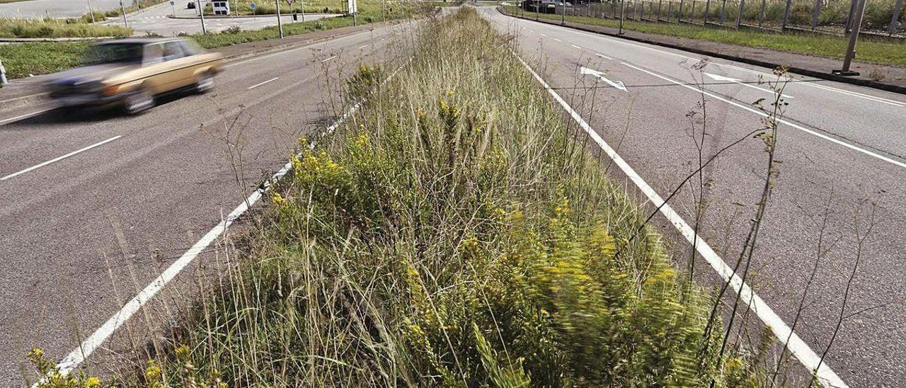 Un vehículo circula en dirección a la carretera del faro de Avilés tras pasar la rotonda de La Palmera.