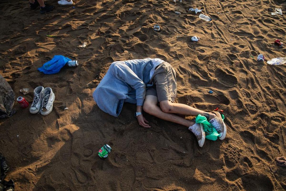 Un joven duerme en la playa de la Barceloneta, la mañana del 24 de junio, tras pasar la verbena en la playa.