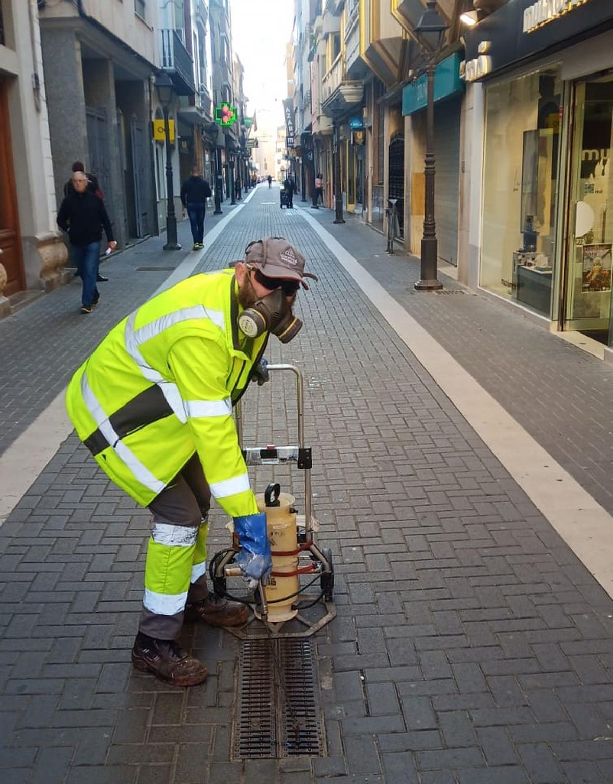 Un operari realitza el tractament antimosquits en un dels embornals del carrer Major de Vila-real.