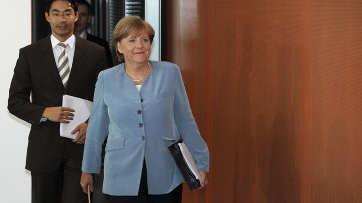 Angela Merkel, seguida de su ministro de Economía, Philipp Roesler, llega a la reunión del gabinete de gobierno, este miércoles, en Berlín.