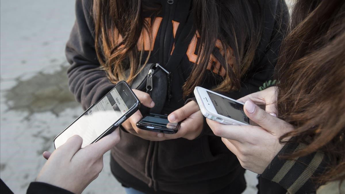 Adolescentes con sus teléfonos móviles. 