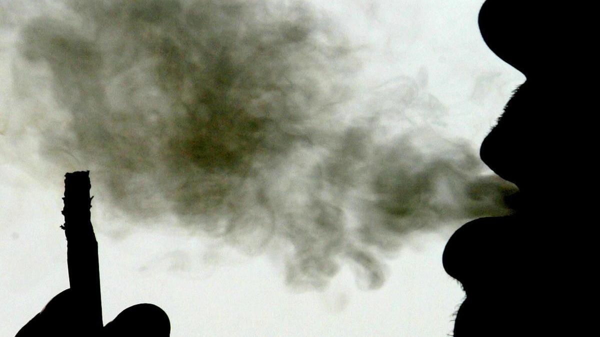 Un hombre exhala una bocanada de humo de un cigarro