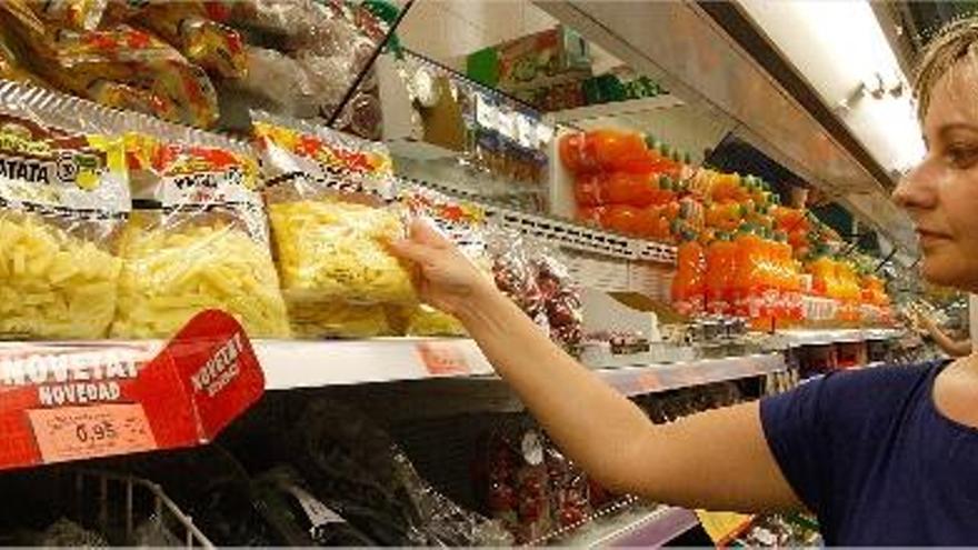 Una mujer coge una bolsa de patatas peladas en una tienda de Mercadona de Valencia.