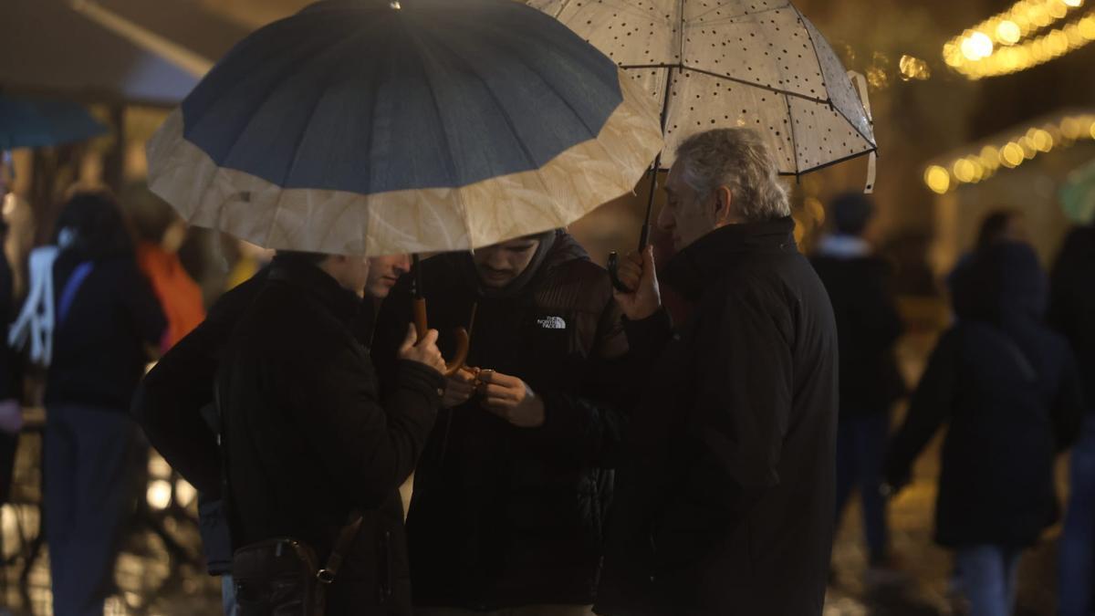 Varias personas se protegen de la lluvia este domingo por la noche en València.