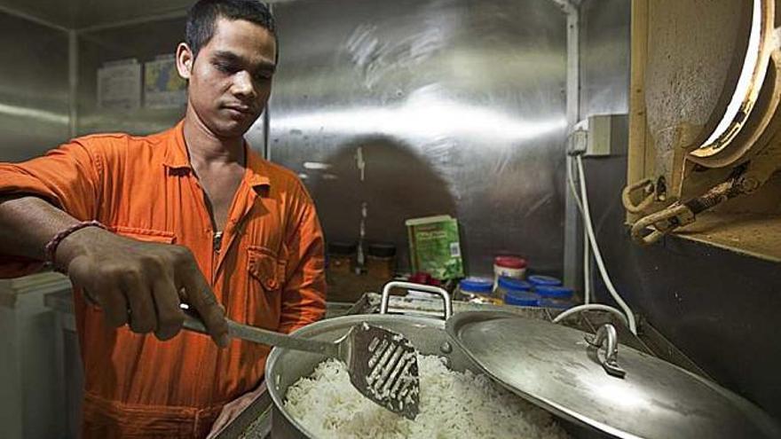 Sanjay Kumar, de 24 años, el cocinero y el benjamín de la tripulación. A la derecha, un momento del almuerzo: pollo masalla, arroz, vino español y después, un cigarrillo