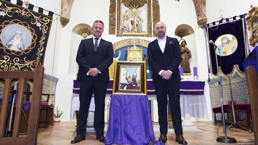 Manuel Calderón y Jesús Ortiz junto al cartel en la parroquia de la Encarnación de El Burgo.