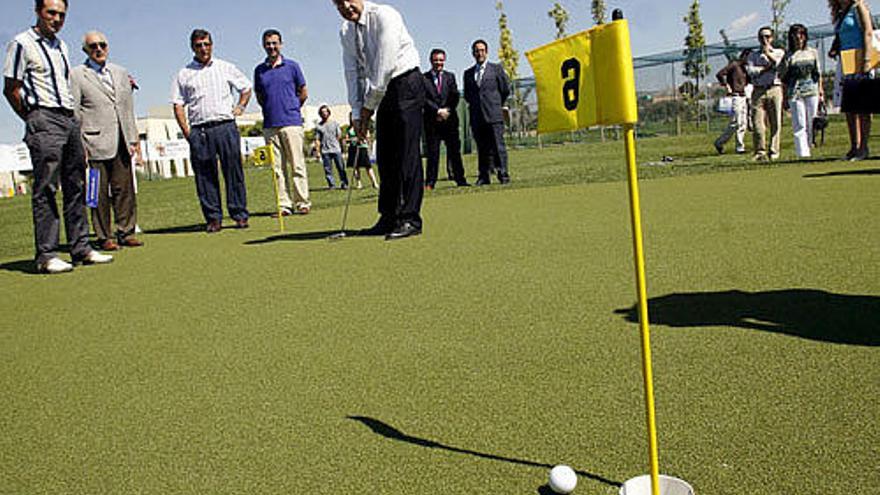 El rector de la Universidad Miguel Hernández de Elche, Jesús Rodríguez Marín (c), intenta embocar durante la inauguración del campo de golf de hierba artificial del campus.