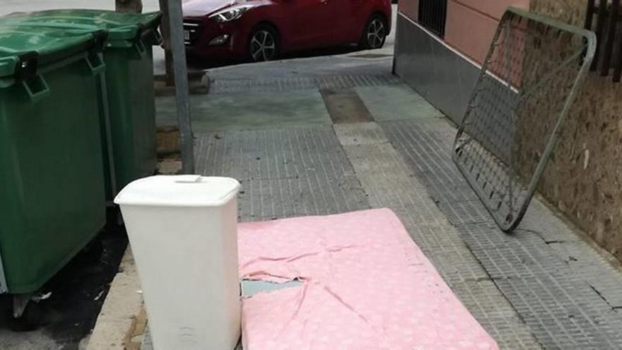 Un somier, un colchón y varios enseres viejos de una vivienda se acumulan junnto a un contenedor en las calles de Cieza.