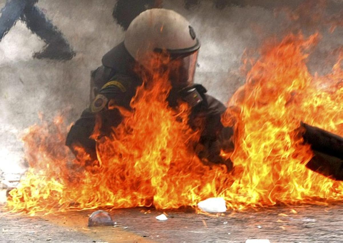 Riot policeman falls after being hit with a molotov còctel during nationwide strike over austerity measures in Athens