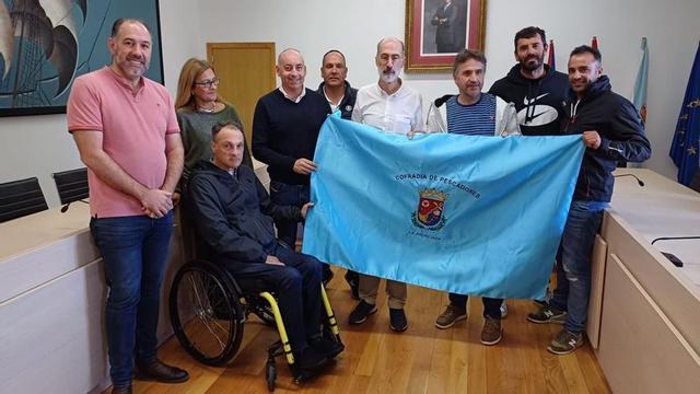 Alcalde y patrón mayor sostienen la bandera de la Cofradía con ediles y miembros del cabildo.