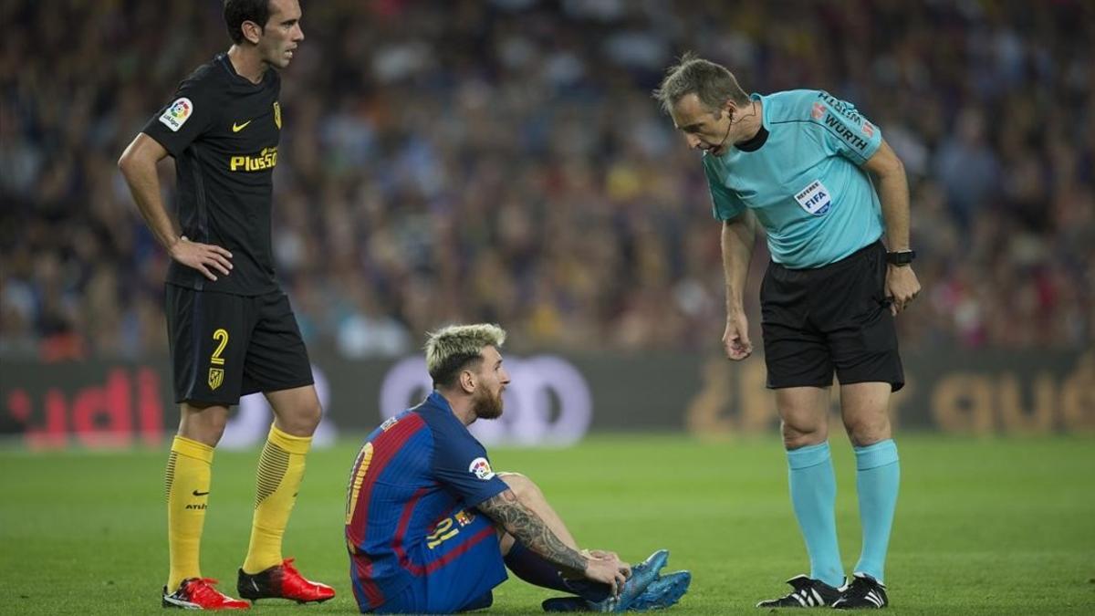 Messi, en el suelo entre Godín y el árbitro, momentos antes de ser sustituido por lesión.