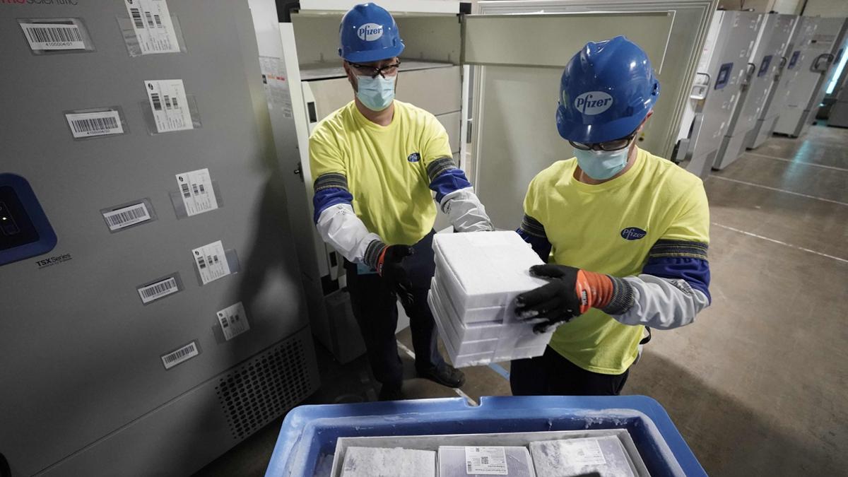 Empleados de Pfizer cargan la vacuna en contenedores.