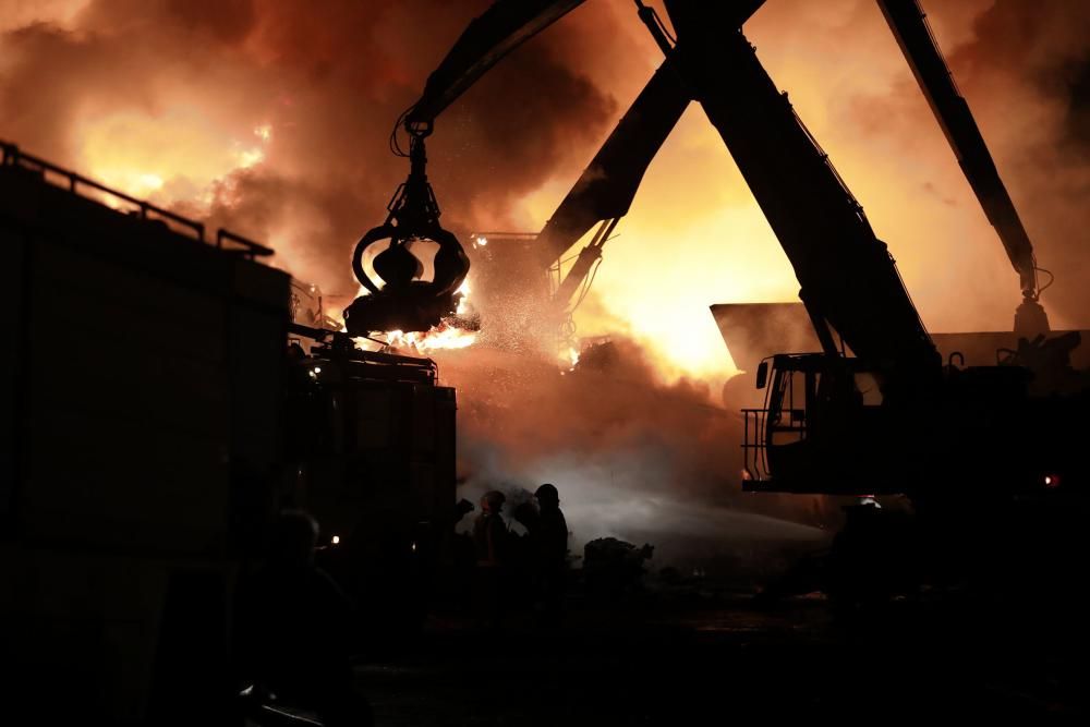 Labores de extinción del incendio de un desguace en Gijón