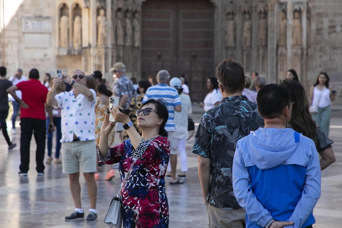 Una turista asiática toma fotos en la plaza de la Virgen de València.