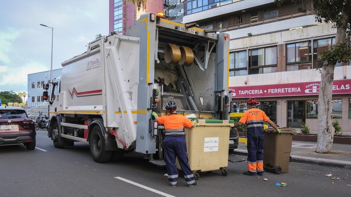 Dos operarios llevan un contenedor a un camión de basura en Las Palmas de Gran Canaria.