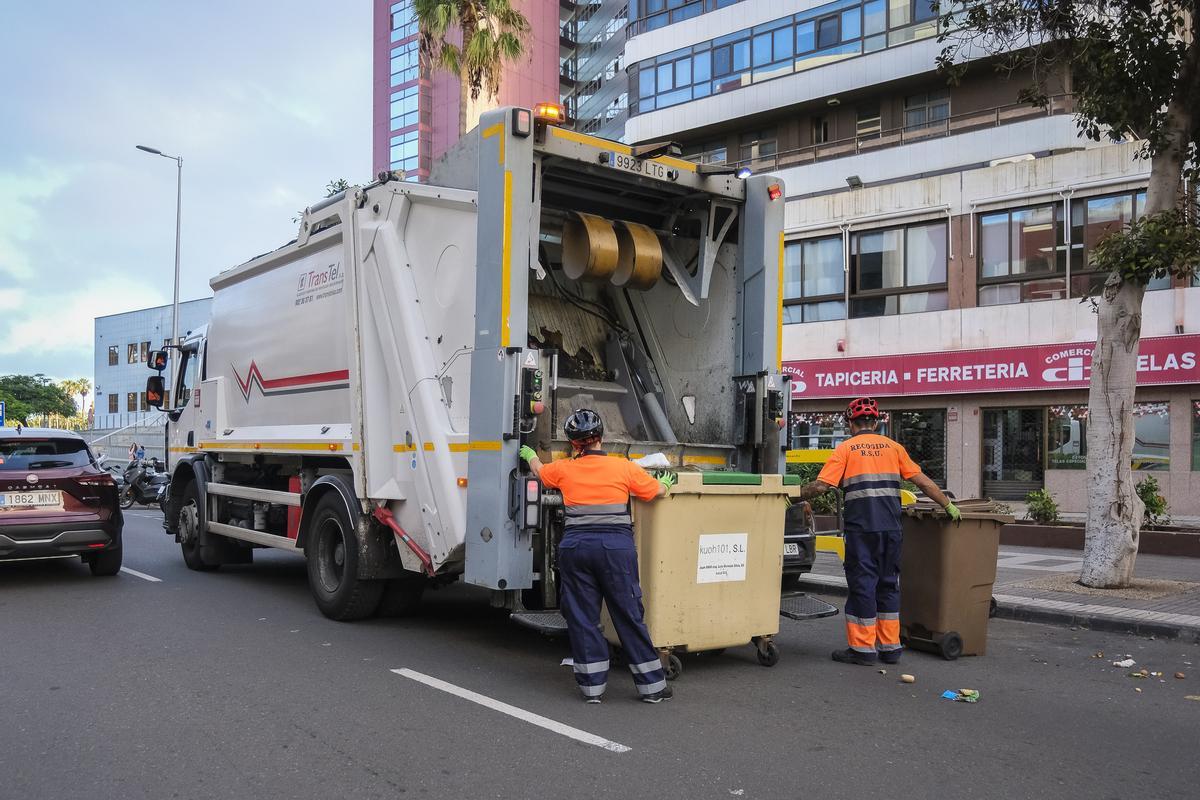 Dos operarios llevan un contenedor a un camión de basura en Las Palmas de Gran Canaria.