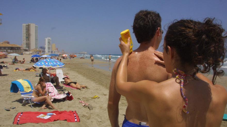 Una mujer le echa protección solar a un hombre en la playa de La Manga