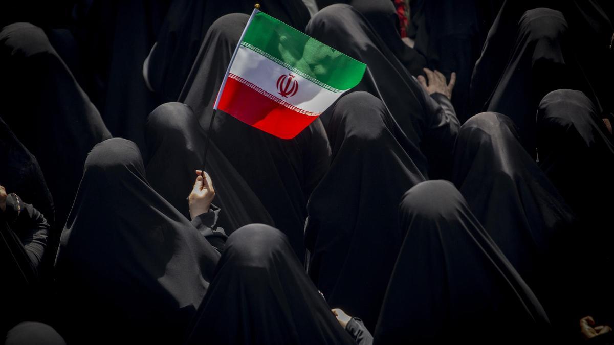 Un grupo de mujeres con burka con una bandera de Irán.