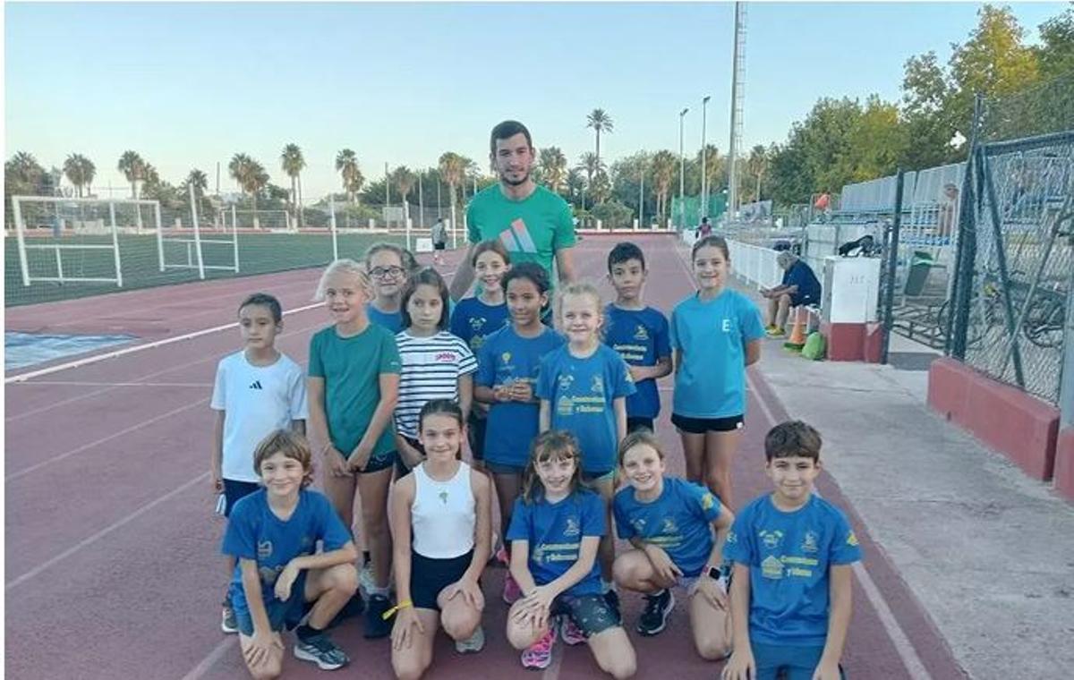 Llopis, en Oliva, posa con un grupo de niños y niñas atletas del Corriol Oliva.