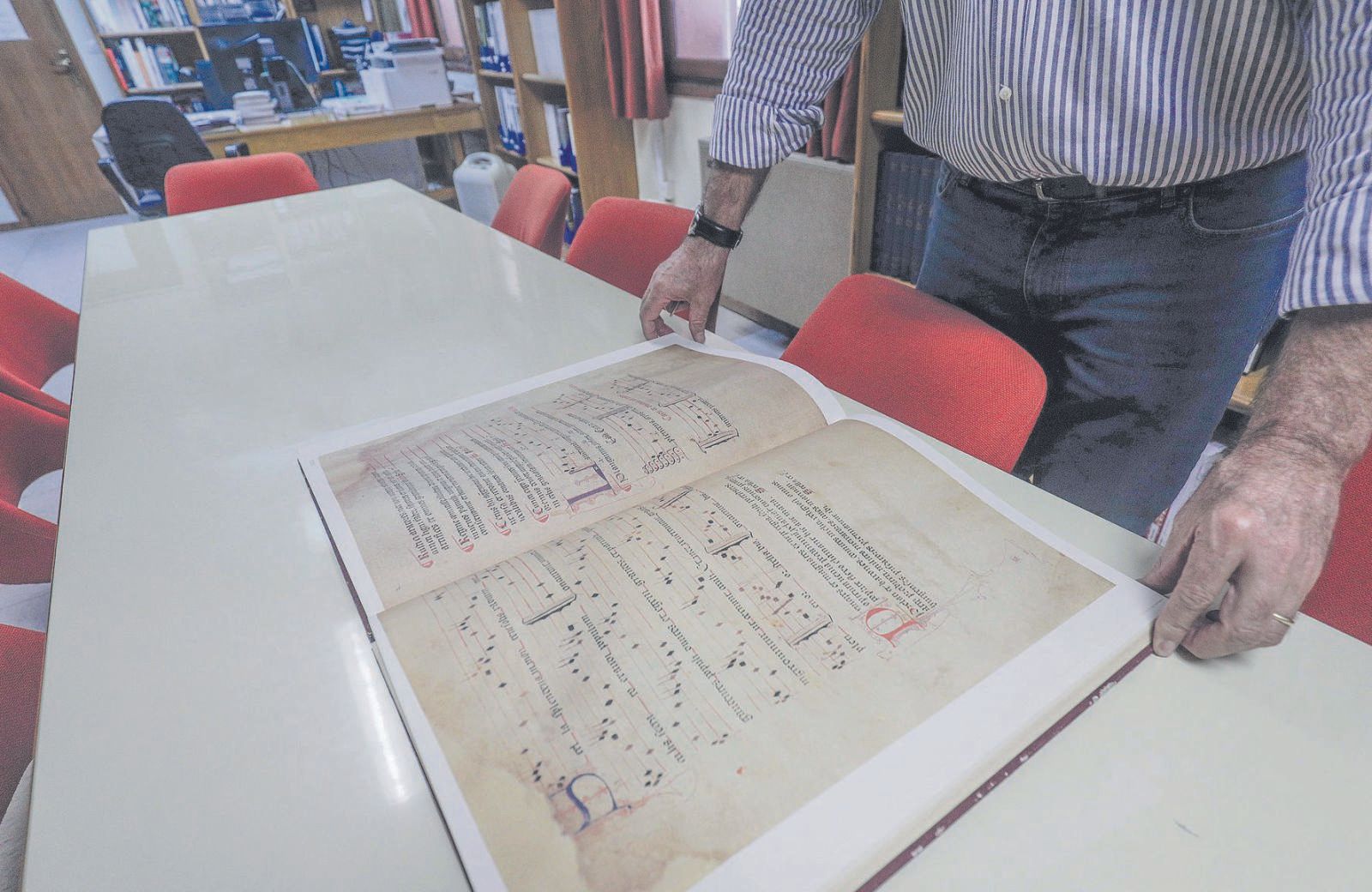 Company muestra uno de los antiguos libros de música.