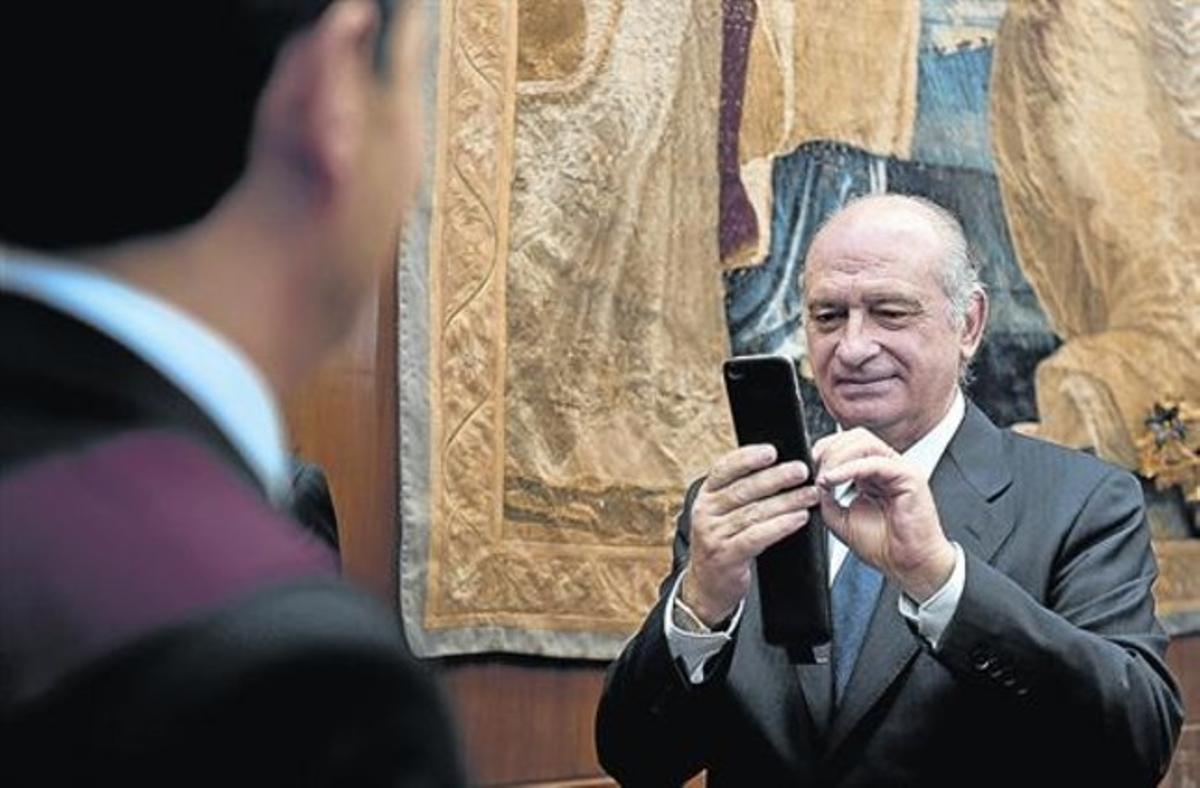 El ministro del Interior, Jorge Fernández Díaz, toma una foto con su móvil durante un acto oficial.