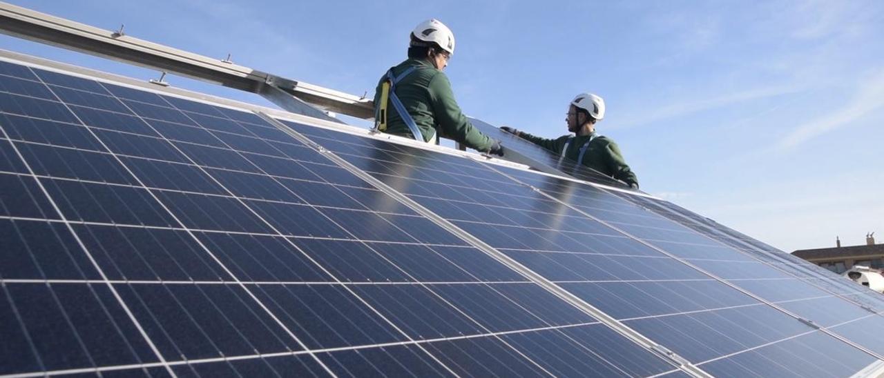 Dos operarios instalan paneles solares para el autoconsumo.