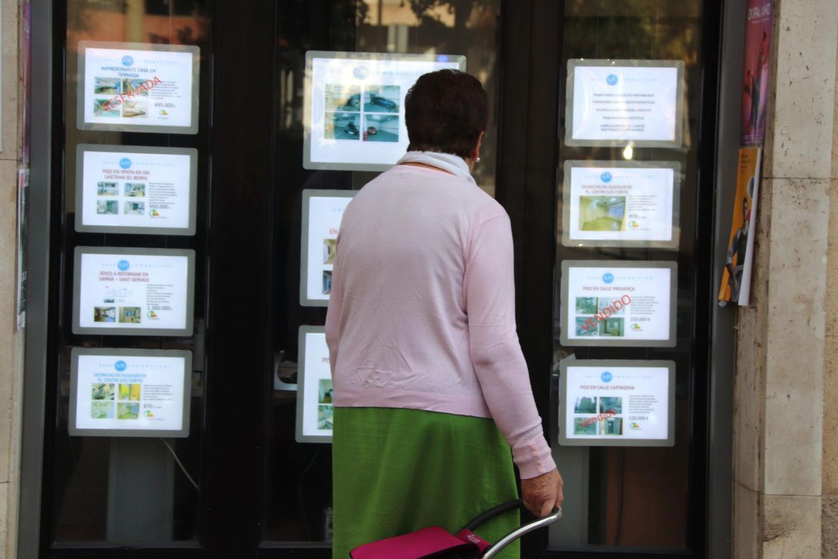 Una mujer revisa las ofertas de pisos a la venta en una inmobiliaria.