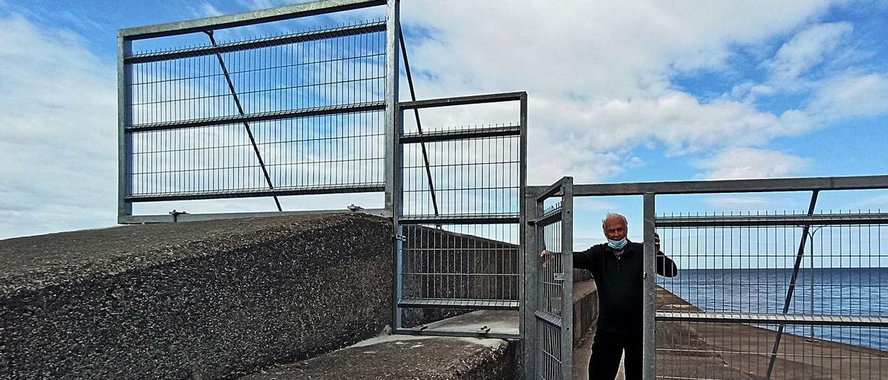 Anselmo Hulton, presidente de la asociación vecinal de San Esteban, junto a una de las vallas instaladas en el dique, en una imagen del pasado marzo. | S. Arias