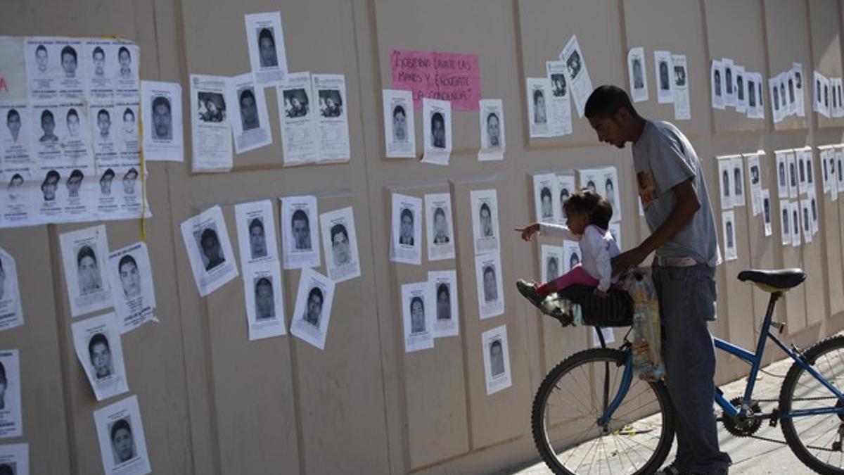 Una niña señala fotografías de los estudiantes desaparecidos, este jueves en un mural en Ciudad Juárez.