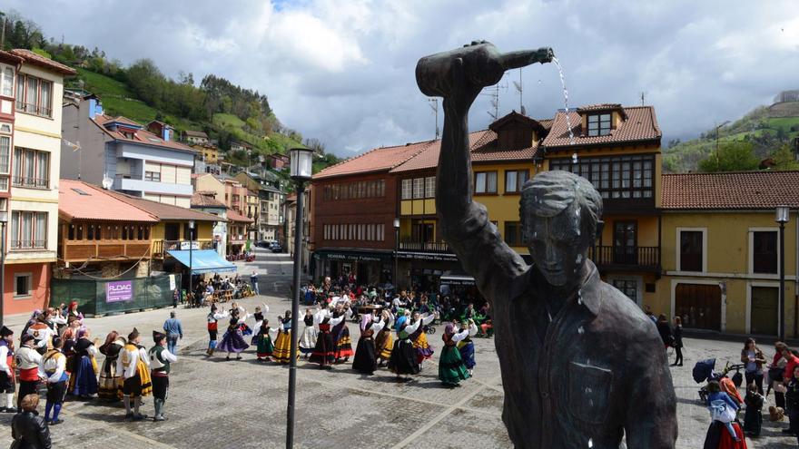 Foto de archivo de una actuación folclórica en la plaza de Requejo, con la escultura dedicada al escanciador en primer término.