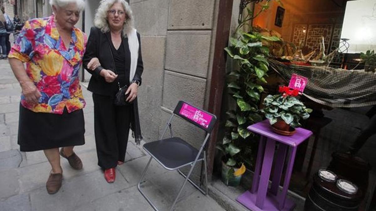 Dolors Obiols (izquierda) y Teresa Caja, junto a una de las sillas de una tienda del Gòtic.