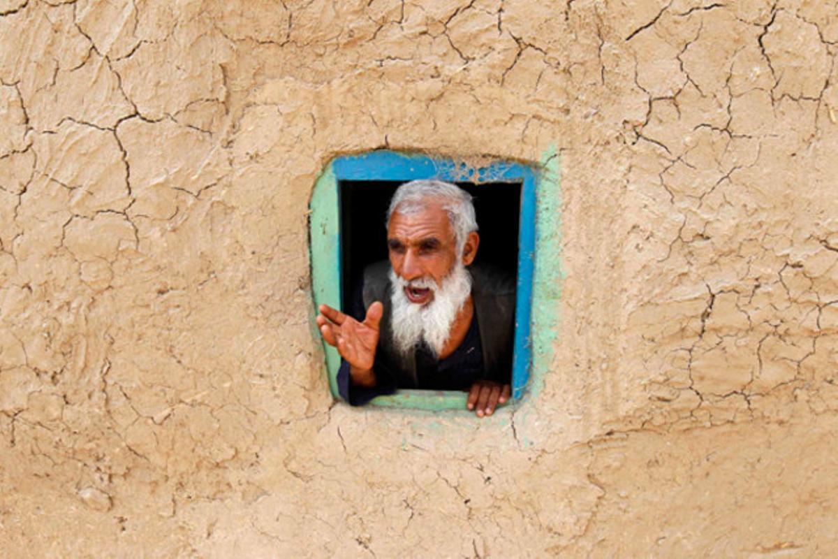 Un desplaçat afganès mira per una finestra al camp de refugiats de Kabul (Afganistan)