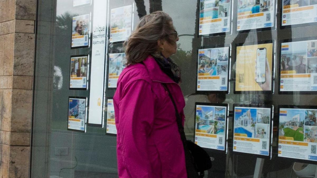 Una mujer consulta los anuncios de una agencia inmobiliaria, de archivo.