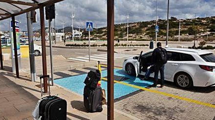 Un taxista conversa con una persona en la parada de la estación marítima de es Botafoc, en Vila.