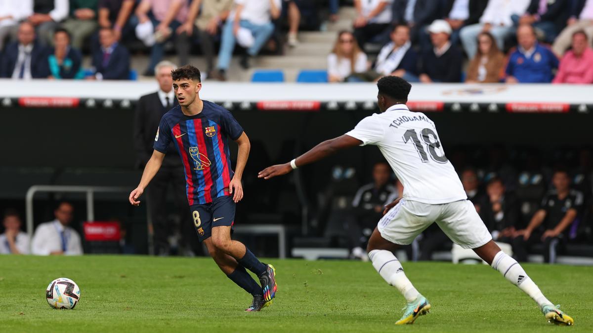 Pedri, jugador del Barça, conduce un balón ante el madridista Tchouaméni en el Clásico disputado en el Bernabéu.