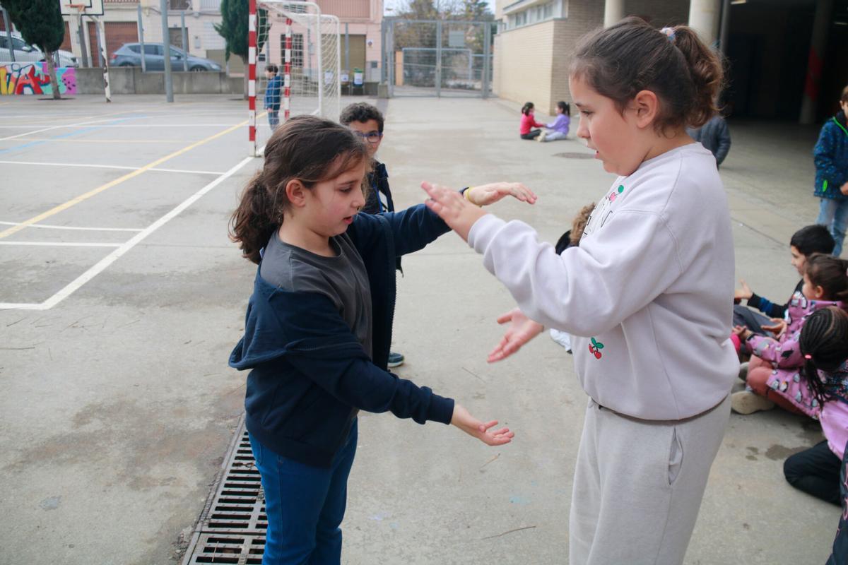 Dues nenes fent el picar de mans al pati.