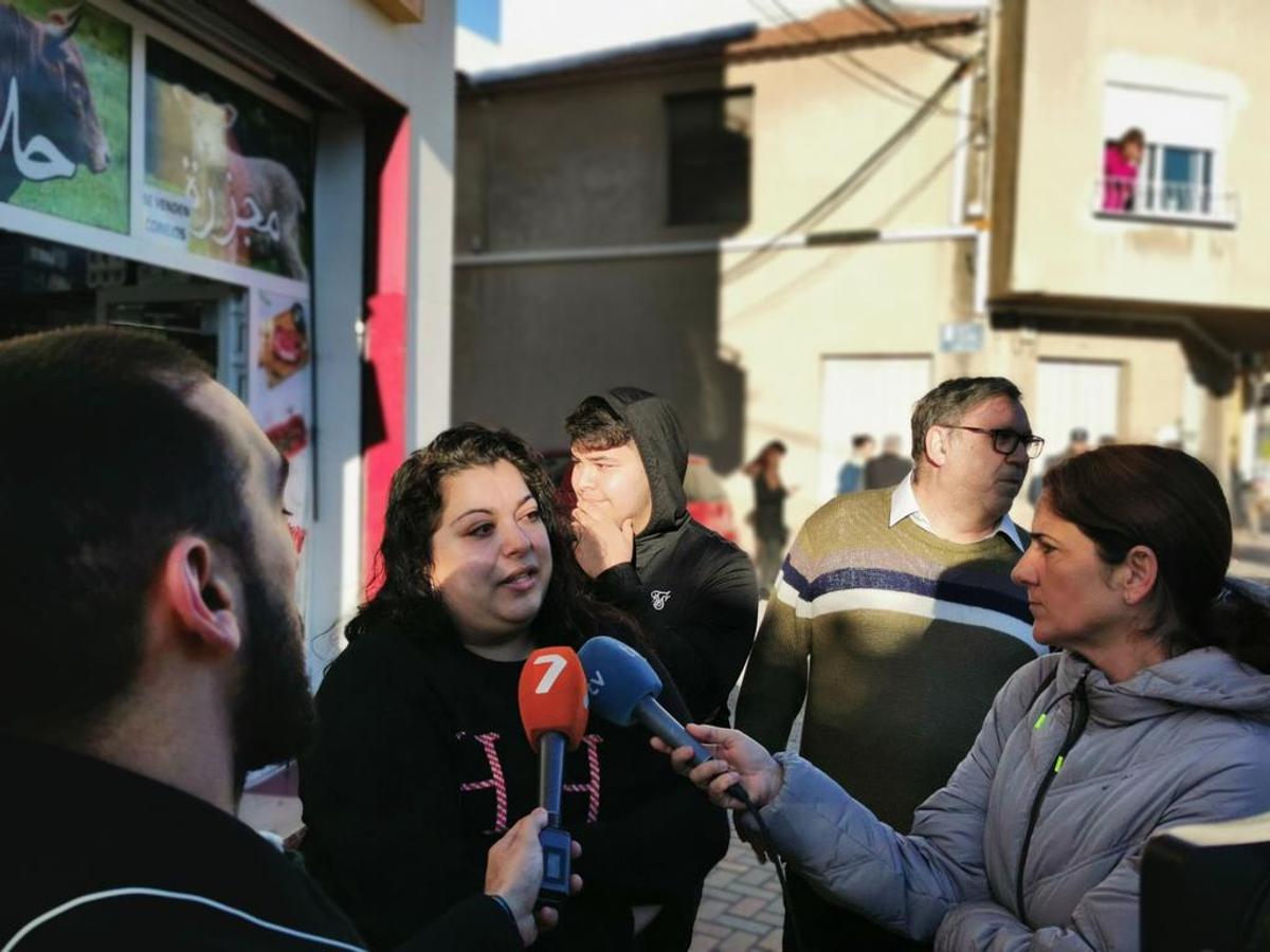 La mujer atiende a los medios; detrás, el cura Joaquín Sánchez y más activistas