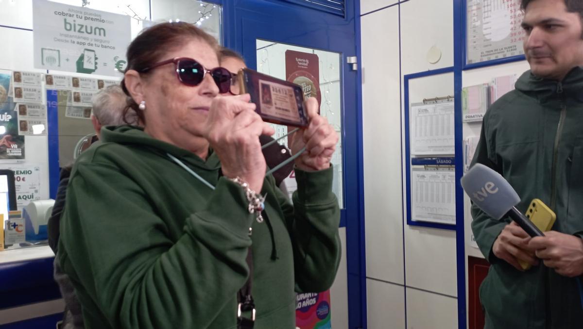 Una de las agraciadas muestra el décimo del quinto premio vendido en Vialia