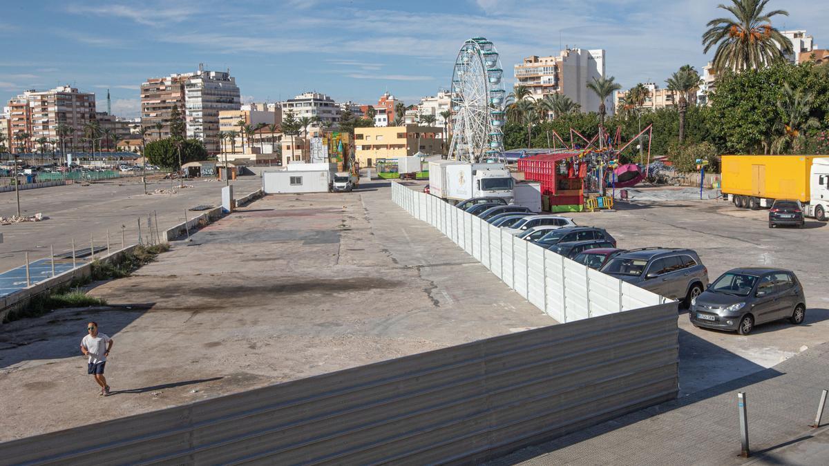 Vallado del perímetro de las obras de la zona de ocio, con las atracciones de feria a la derecha, en una imagen de finales de 2022