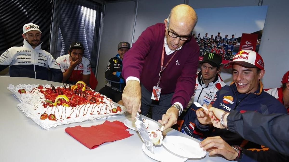 Carmelo Ezpeleta reparte el pastel de su 70 cumpleaños entre los pilotos de MotoGP.