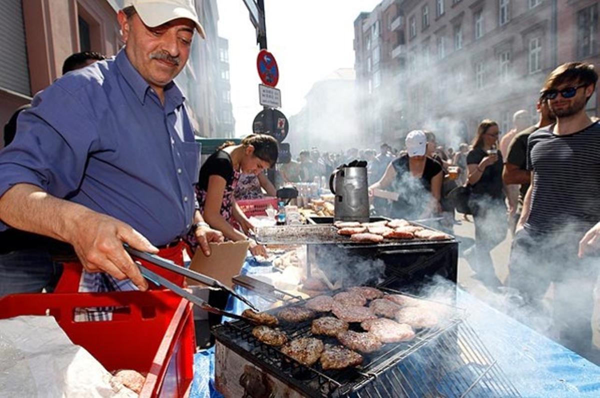 Un home fregeix hamburgueses durant la tradicional festivitat MyFest, al districte berlinès de Kreuzberg.