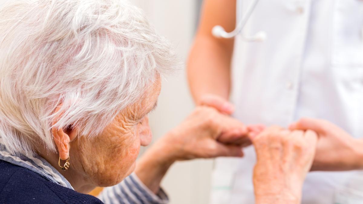 Una joven sanitaria tiende la mano a una mujer mayor