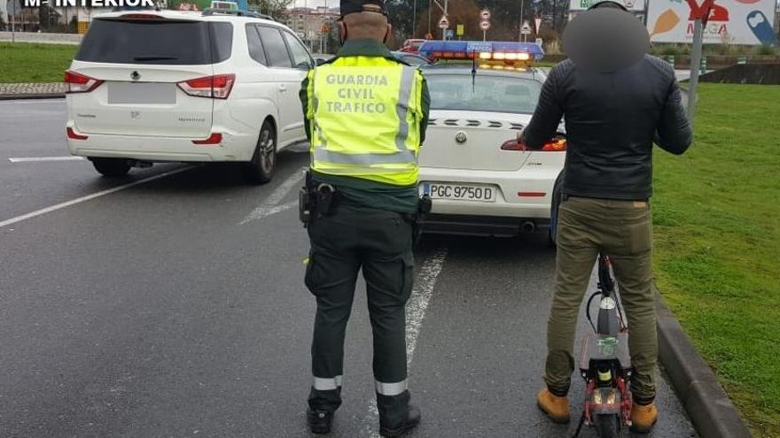 Agentes de Tráfico en Lérez con la persona que fue interceptada con este patinete eléctrico.