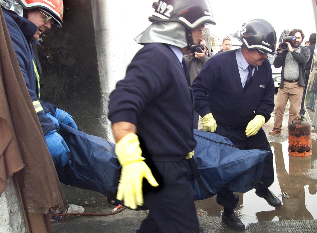 Operarios de la funeraria y bomberos sacan los cadáveres de los dos chinos asesinados.