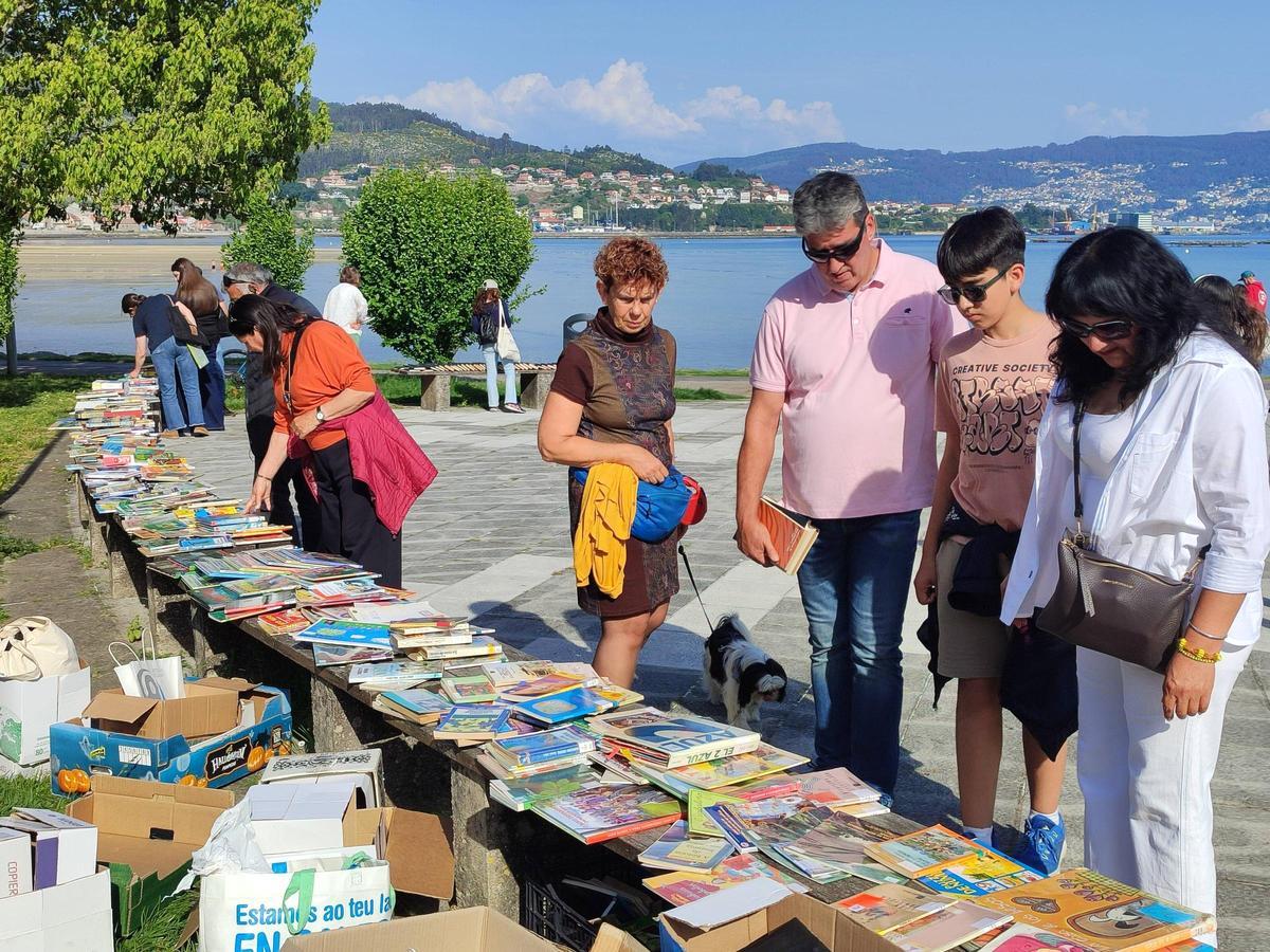 Público viendo el puesto de reparto gratuito de libros en el paseo marítimo de Moaña.