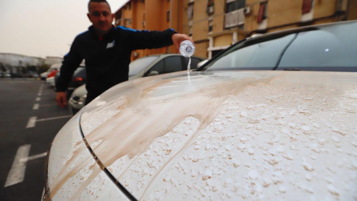 Un hombre intenta limpiar el barro acumulado en su vehículo.