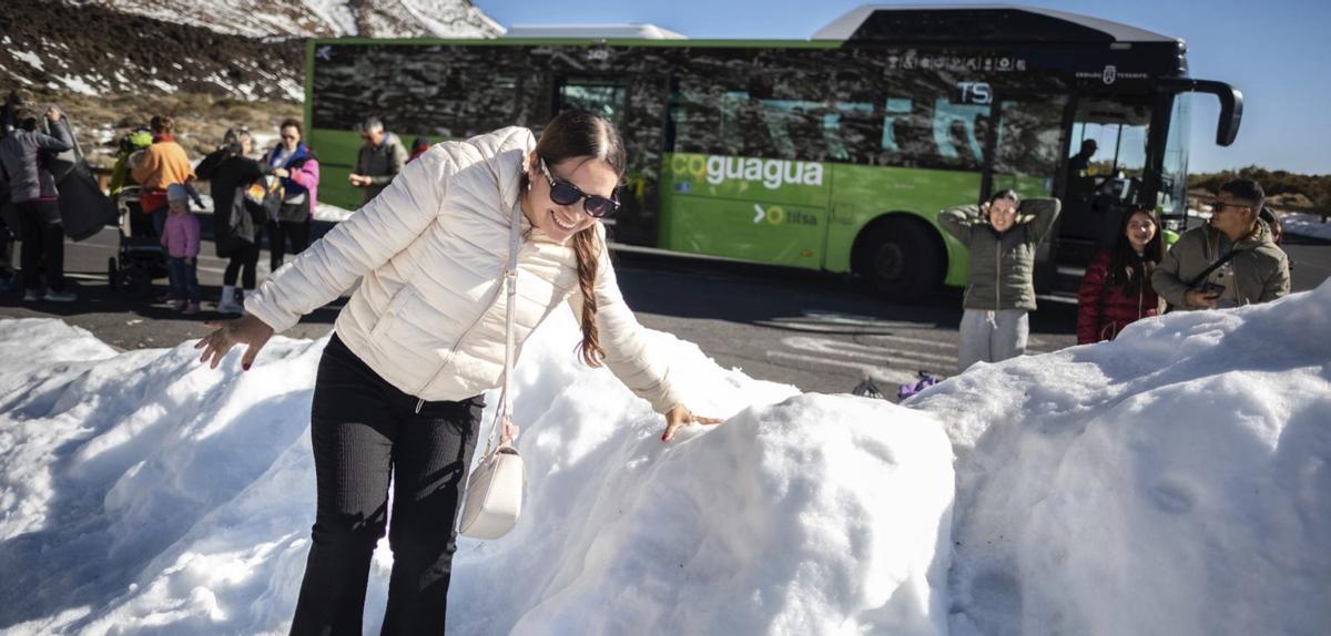 Una mujer en la nieve delante de una guagua lanzadera en el Parque Nacional del  Teide durante el Operativo Nevada del pasado 20 de diciembre.  | ANDRÉS GUTIÉRREZ