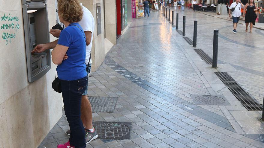 Unos clientes sacan dinero de un cajero en Málaga.